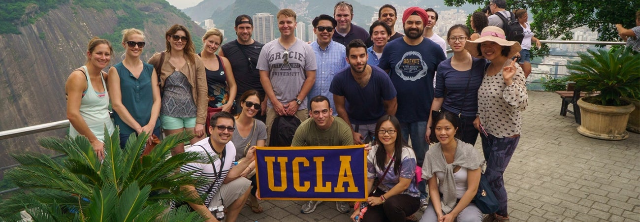 A group of 20 CGM students in Hong Kong posing with a UCLA banner